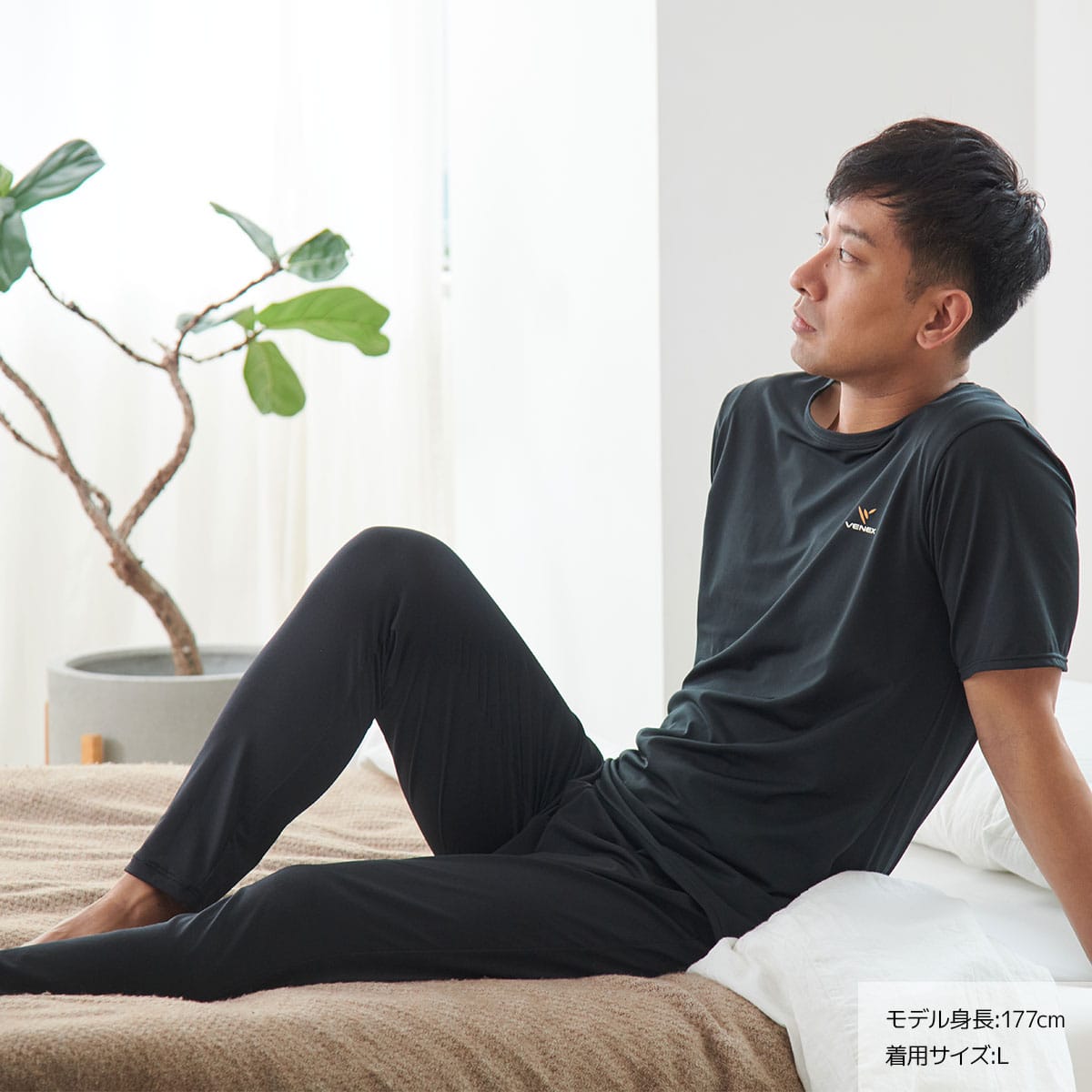 ベネクスのリフレッシュ メンズを着てベッドにもたれる男性モデル