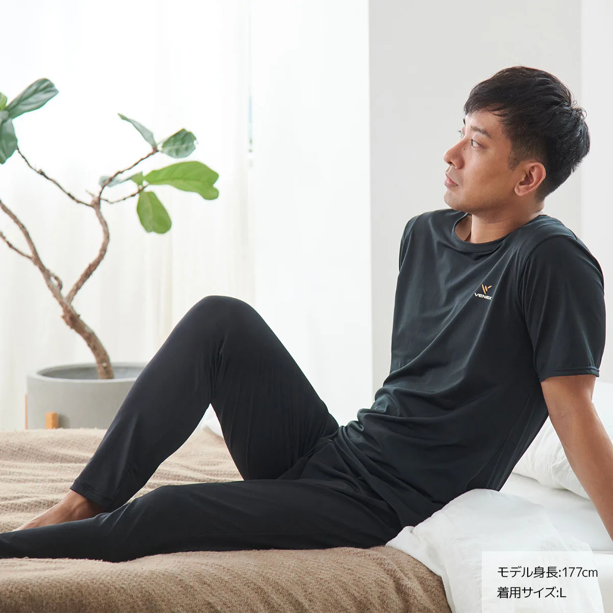 ベネクスのリフレッシュ メンズを着てベッドにもたれる男性モデル