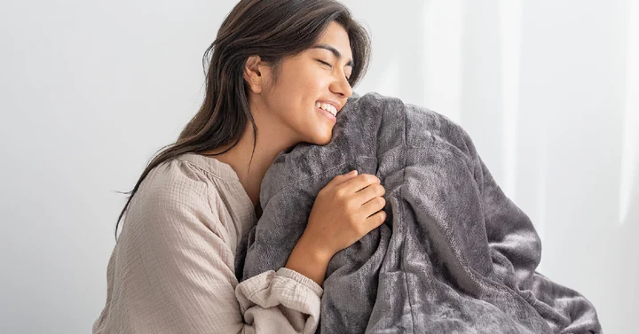 クリーニングで仕上がった掛け布団を抱える女性